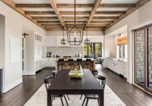 Wood beams and elegant pendant lights accent this beautiful open-plan dining room and kitchen in new home